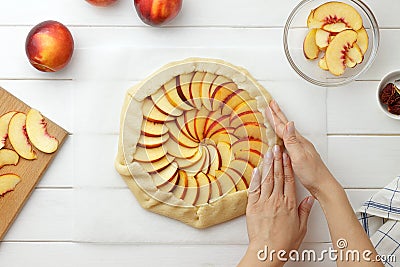Step by step recipe galette or pie with nectarines. Female hands wrapping edges of dough around filling. Stock Photo