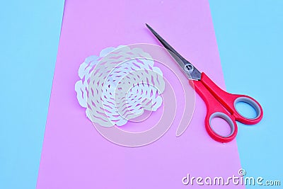 step-by-step process of cutting out snowflakes from white paper for new year and Christmas on the background of bed tones Stock Photo