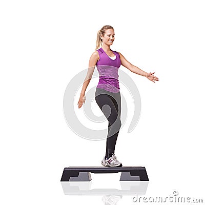 Stepping towards better fitness. A smiling young woman doing aerobics on an aerobic step against a white background. Stock Photo