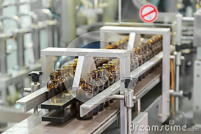 Sterile bottles on the production line conveyor of the pharmaceutical industry. Machine for iquid drugs glassware bottling. Stock Photo