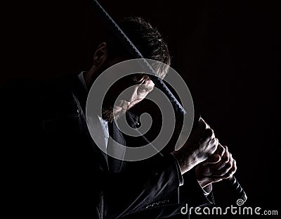 Stern angry businessman in a wool coat with sword in dark background Stock Photo