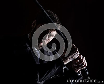 Stern angry businessman in a wool coat with sword in dark background Stock Photo