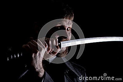 Stern angry businessman in a wool coat with sword in dark background Stock Photo