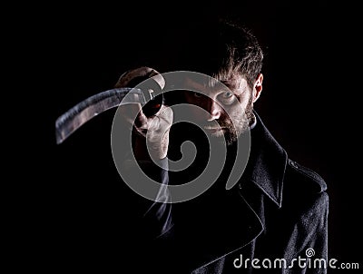 Stern angry businessman in a wool coat with sword in dark background Stock Photo