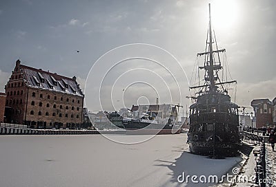 Stern of a sailshship mooring in ice during winter in Old Town of Gdansk Poland. Old town in the background. Editorial Stock Photo