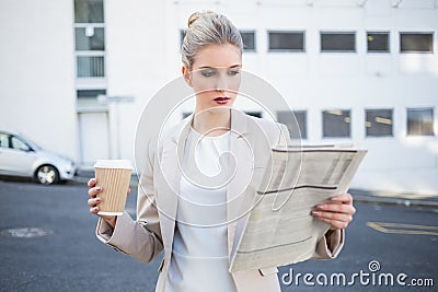 Stern stylish businesswoman reading newspaper Stock Photo