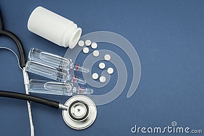 Stethoscope along some medicines and vials on blue background Stock Photo