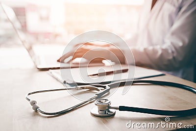 Stethoscope and background doctor using laptop at desk in clinic Stock Photo