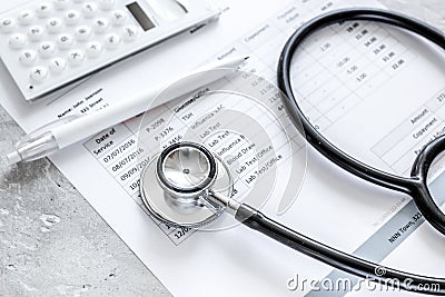 Stethoscope, billing statement for doctor`s work in medical center stone background Stock Photo