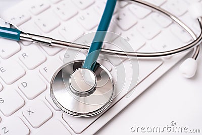 Stethoscope on computer keyboard on white background. Physician write medical case long term care treatment concept, close up, Stock Photo