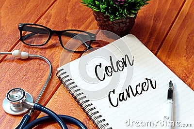 Stethoscope,eyeglasses,plant,pen and book written with Colon Cancer on wooden background, Health concept. Stock Photo