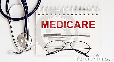 Stethoscope,glasses and pen with notepad with text medicare Stock Photo