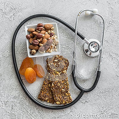 Stethoscope and heart with dried fruits and nuts on a gray background Stock Photo