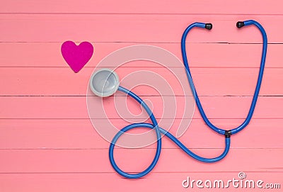 Stethoscope and heart on pastel pink wooden table. Cardiology equipment for diagnosing cardiovascular diseases. Top view. Stock Photo