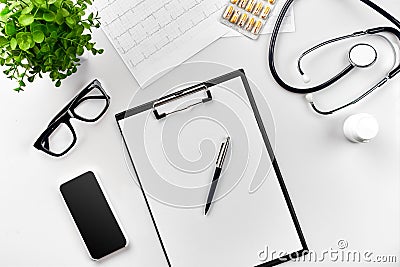 Stethoscope in the office of doctors. Top view of doctor`s desk table, blank paper on clipboard with pen. Copy space Stock Photo