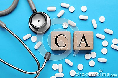 Stethoscope, pills and calcium symbol made of wooden cubes with letters on light blue background, flat lay Stock Photo