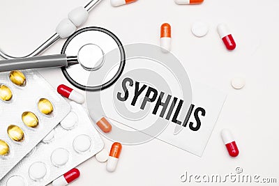 Stethoscope, pills and notebook with Syphilis word on medical desk Stock Photo