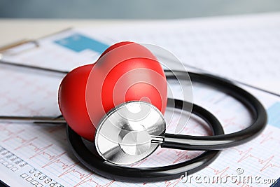 Stethoscope, red heart and cardiogram on table. Stock Photo