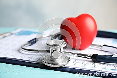 Stethoscope, red heart and cardiogram on table. Cardiology Stock Photo