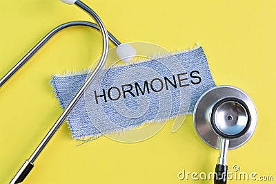 Stethoscope and ripped pieces of jeans with text HORMONES Stock Photo