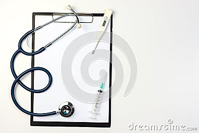 Stethoscope, syringe and thermometer on clipboard with blank paper Stock Photo