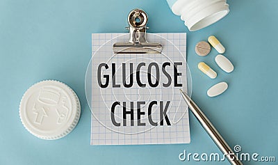 Stethoscope and white card with GLUCOSE CHECK text on blue background. Medical concept Stock Photo