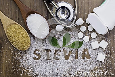 Sugar and Stevia leaf, sweetener tablets and medical stethoscope on wood table background. Stock Photo