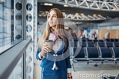 Stewardess with hand luggage and coffee in airport Stock Photo