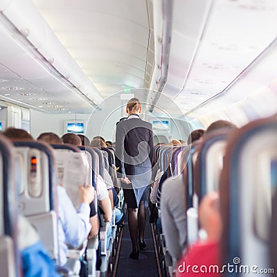 Stewardess and passengers on commercial airplane. Stock Photo