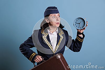 Stewardess running late at airport, holding retro alarm clock Stock Photo