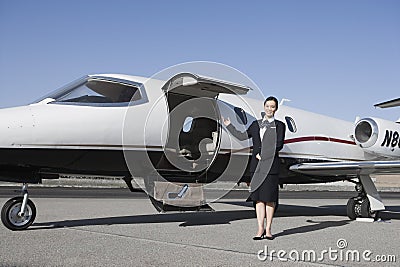 Stewardess Standing By Airplane At Airfield Stock Photo