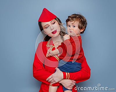 Stewardess wearing in red uniform with a child on hands Stock Photo