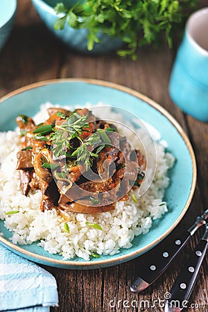 Stewed liver in a sauce with onion, carrot and parsley and boiled rice. Stock Photo