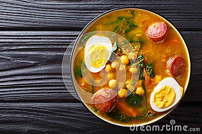 Stewed Potaje de garbanzos chickpeas, spinach, chorizo sausages, boiled eggs close-up in a bowl. horizontal top view Stock Photo