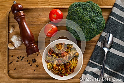 Stewed tomatoes with broccoli in a plate on a wooden background Stock Photo