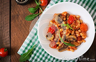 Stewed white beans with mushrooms and tomatoes with spicy sauce in a white bowl. Stock Photo