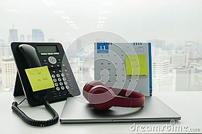 Stick note call back message and check e-mail on IP phone and November calendar for employee reminder with notebook computer an Stock Photo