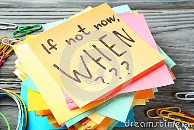 Sticker papers with inspirational phrase If not now, WHEN??? on wooden table Stock Photo