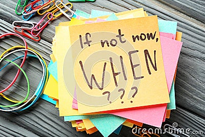 Sticker papers with inspirational phrase If not now, WHEN??? on wooden table Stock Photo