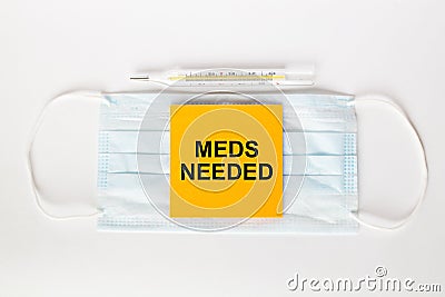 Sticker with text Meds Needed lying on the mask with a thermometer Stock Photo