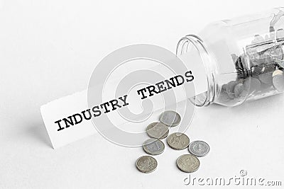 Sticking out of a jar of coins a piece of paper with a text INDUSTRY TRENDS on a white background Stock Photo