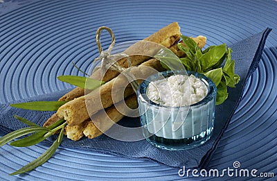 Sticks with feta cheese, tied with string, blue background, white dip, herbs Stock Photo