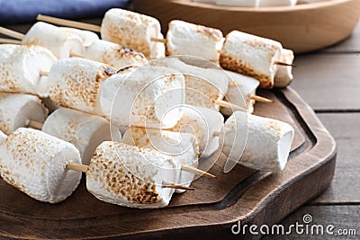 Sticks with roasted marshmallows on wooden table, closeup Stock Photo