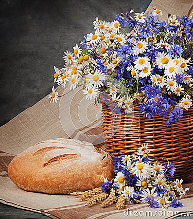 Still Daisies and cornflowers in the basket. Bread and milk on t Stock Photo