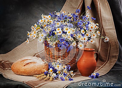 Still Daisies and cornflowers in the basket. Bread and milk on t Stock Photo