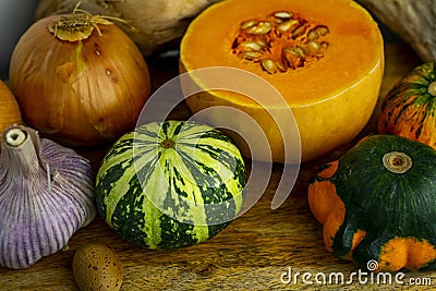 Still life with autumn vegetables and fruits on wooden background. Pumpkins, butternut, garlic Stock Photo