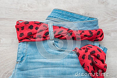 Still life of blue jeans with a brown leather belt on a light wood background Stock Photo