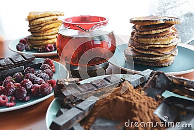 still life on blue plates pancakes with peas, grated chocolate, chocolate bars, brewed tea Stock Photo
