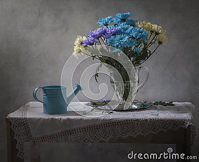 Still life with blue watering can and a bouquet of chrysanthemums Stock Photo