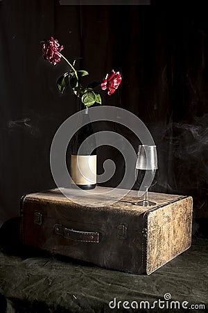 still life bottle and glass of wine with red roses, high contrast, black background Stock Photo